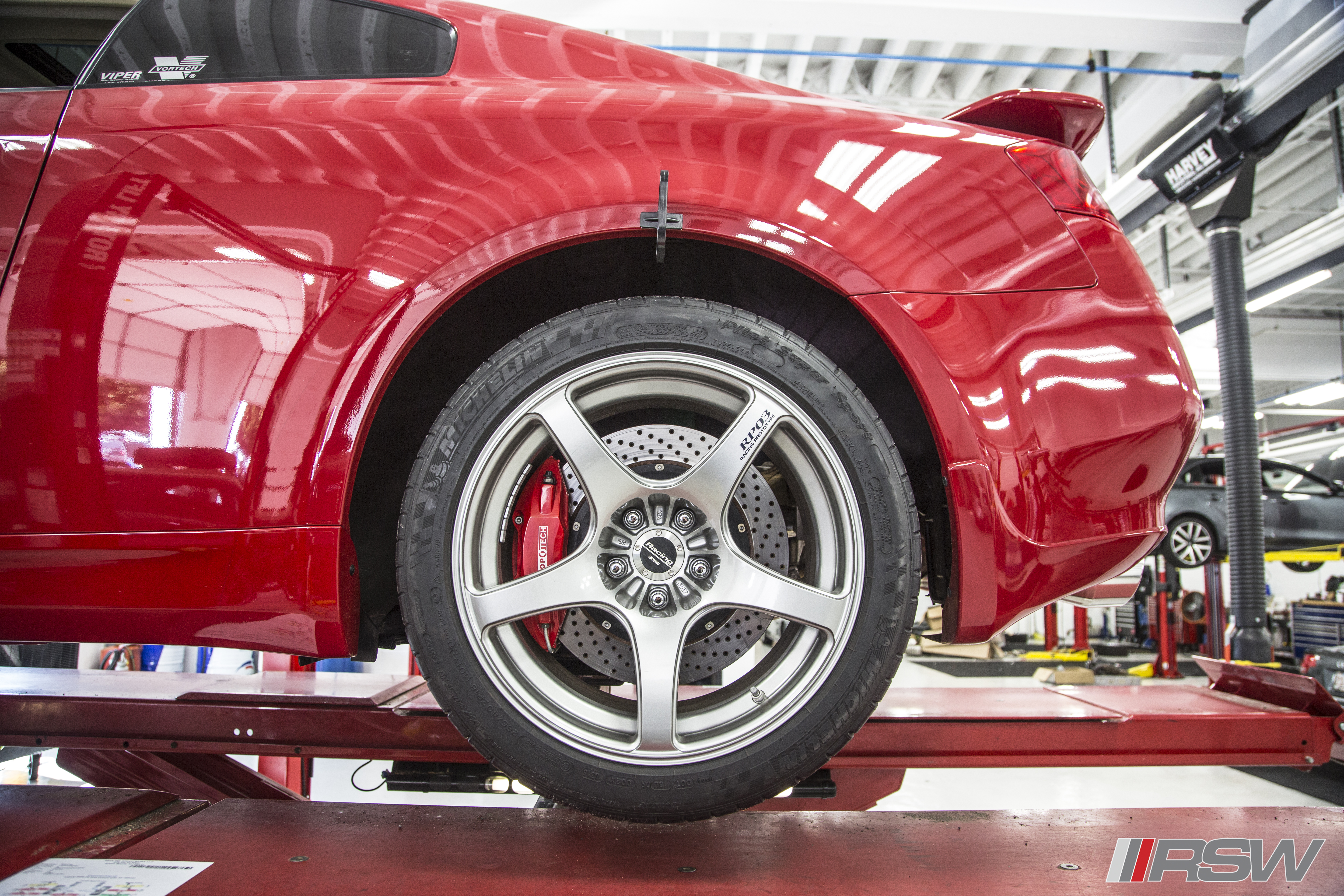 Red Infiniti G35 wheel and StopTech brakes on the lift